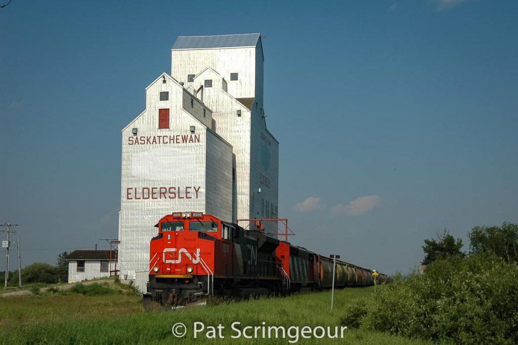 CN 8009 rolls past the Eldersley, SK grain elevator, June 2006. Contributed by Pat Scrimgeour.