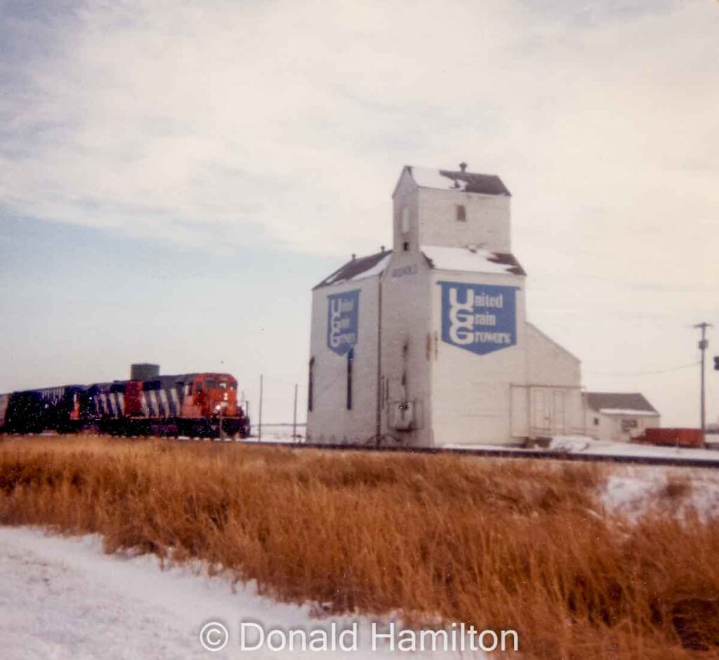 A train passes the Rignold UGG grain elevator, December 1990. Copyright by Donald Hamilton.