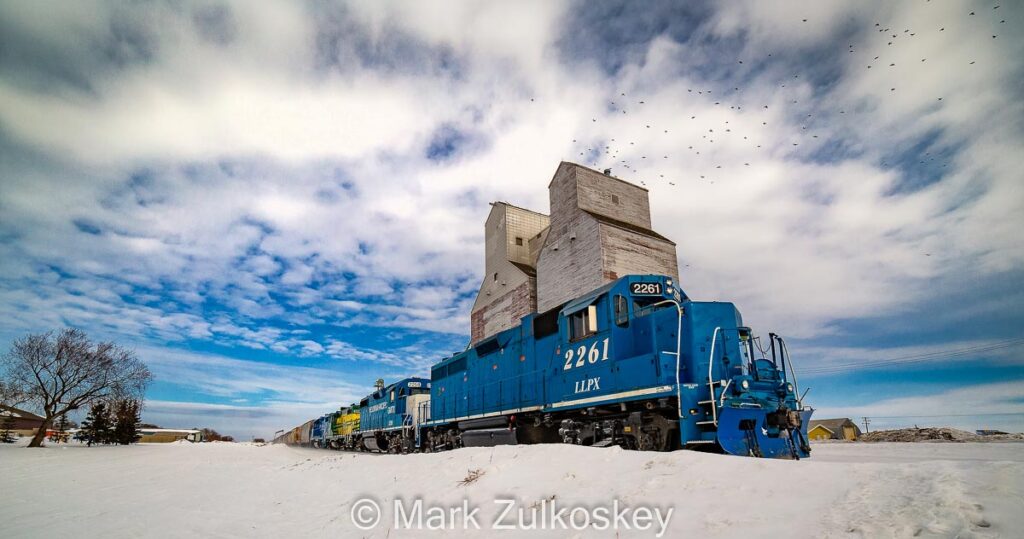 Train and Duck Lake, SK grain elevator, 2021. Contributed by Mark Zulkoskey.
