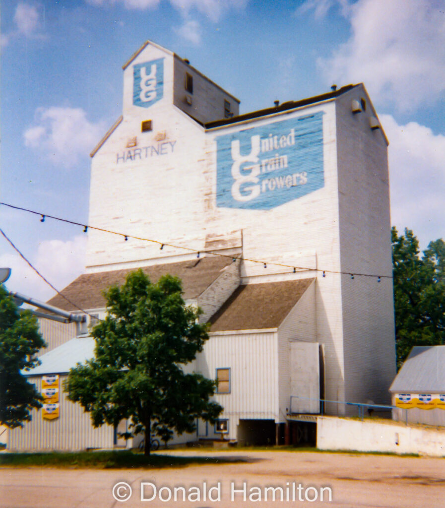 Large white UGG grain elevator in Hartney, Manitoba