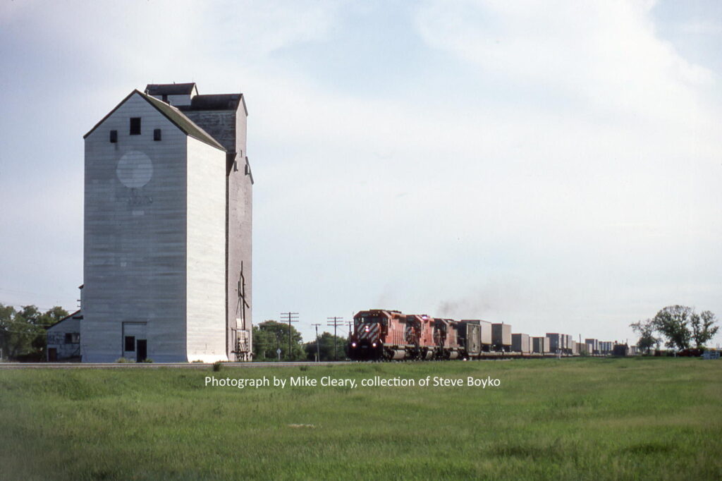 A CP train passing the Douglas, Manitoba grain elevator, June 1986. Photo by Mike Cleary.