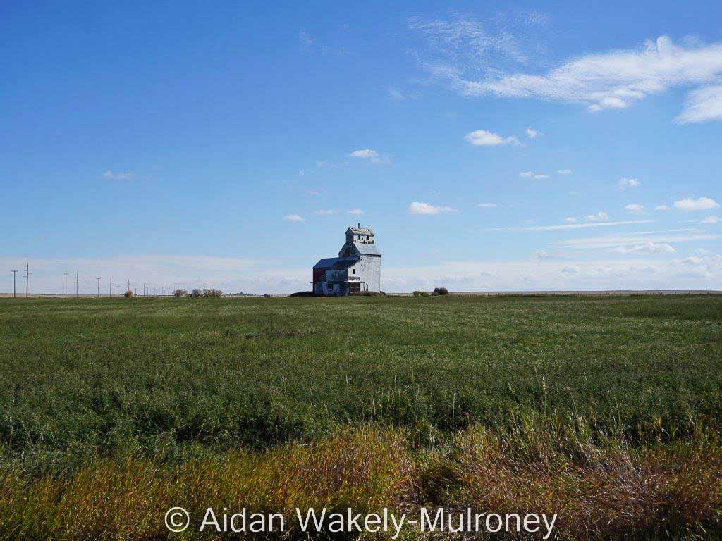 Lonely grain elevator on the prairie under blue skies