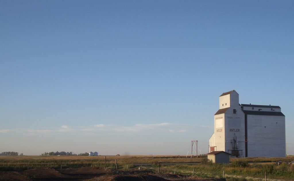 Photograph of wooden grain elevator on the prairie under a blue sky