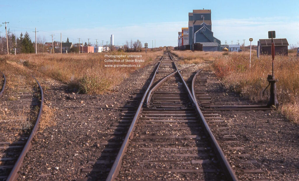 View down a track toward a row of grain elevators