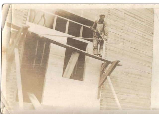 Black and white photograph of a male carpenter building a grain elevator